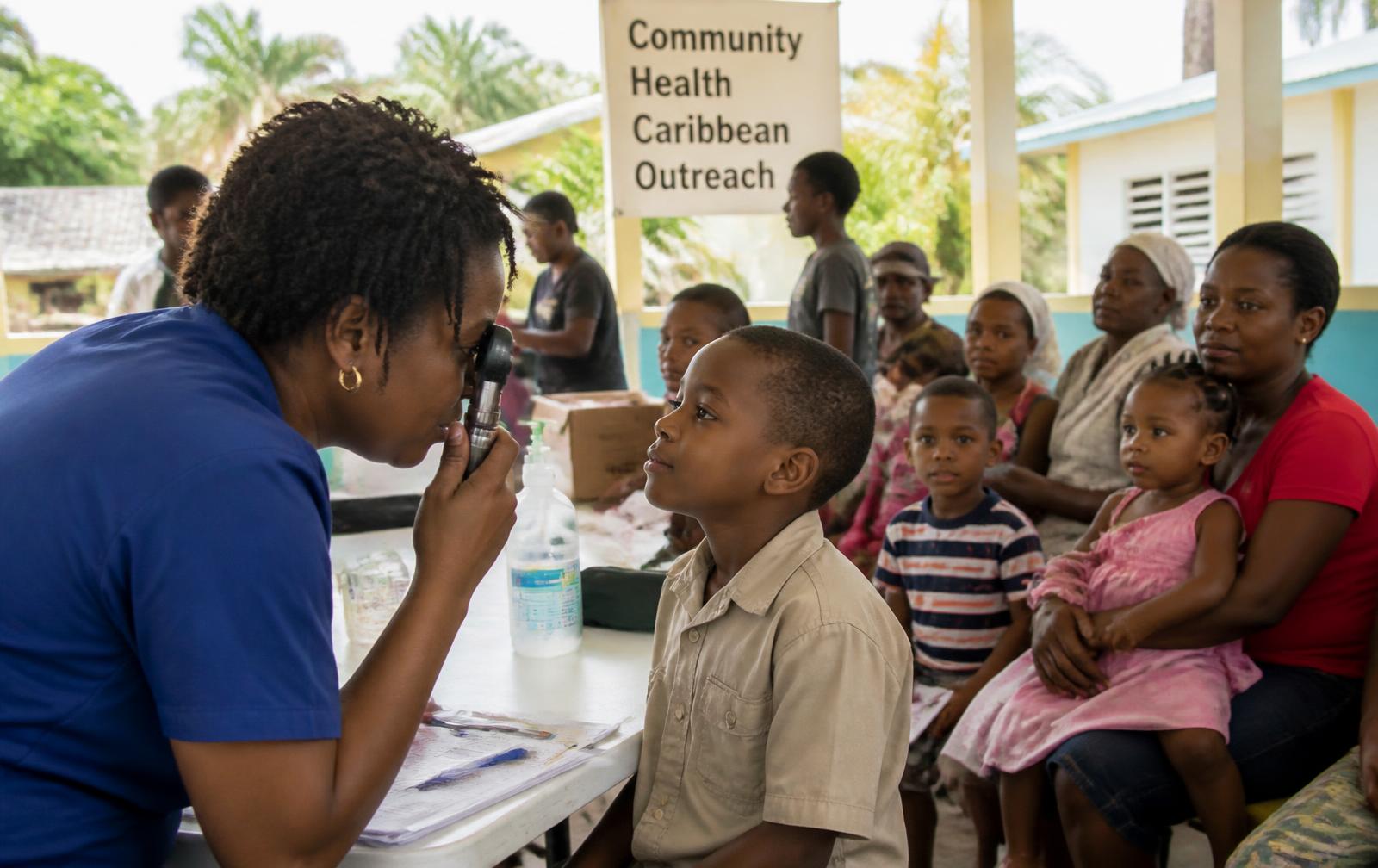 A volunteer nurse performing a vision screening for a child during an outreach clinic